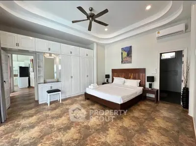 Spacious bedroom with elegant design, featuring a ceiling fan, ample storage, and modern decor.