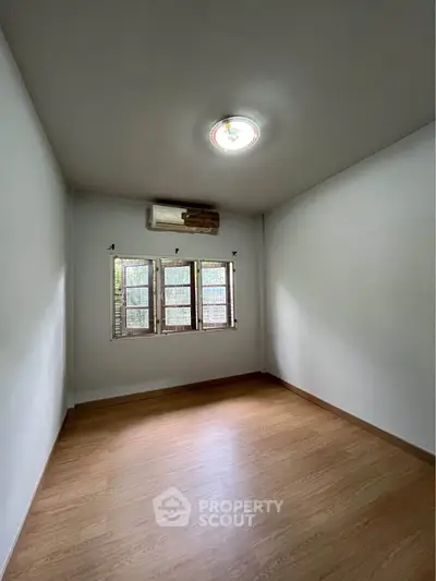 Spacious empty room with wooden flooring and natural light from window, ideal for customization.