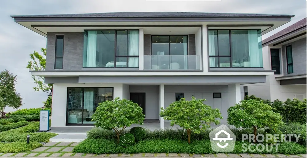 Modern two-story house with large windows and lush landscaping