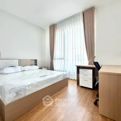 Bright and airy bedroom with modern furnishings and large window, perfect for a serene living experience.