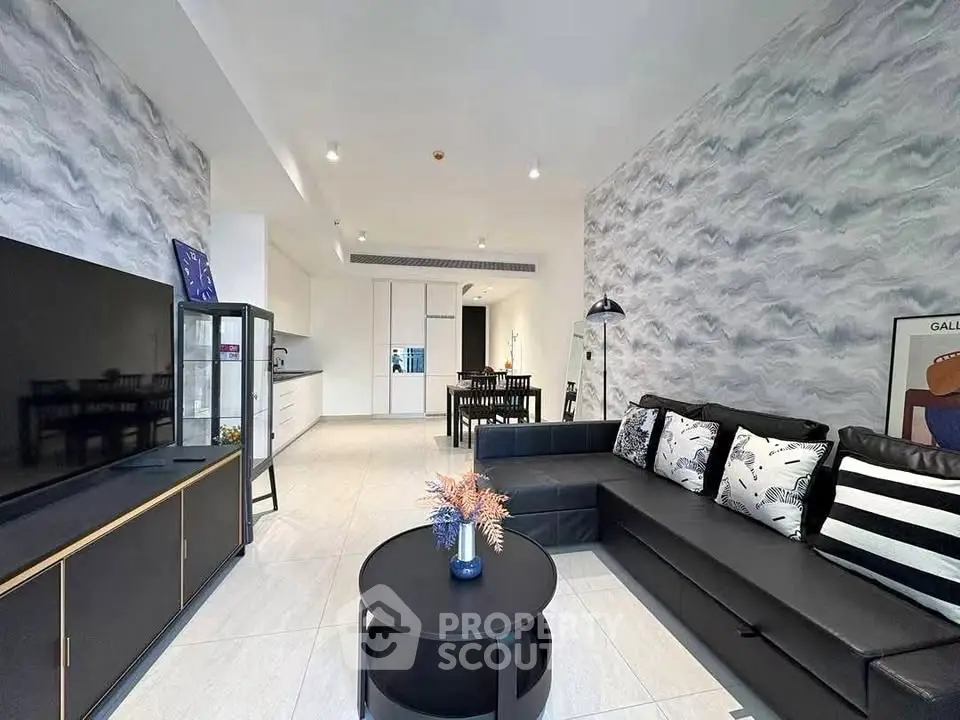 Modern living room with stylish decor and open layout, featuring a sleek black sofa and contemporary furnishings.