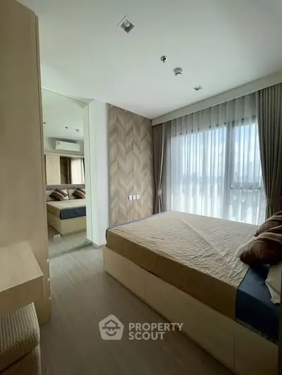 Modern bedroom with stylish decor and large window offering natural light.