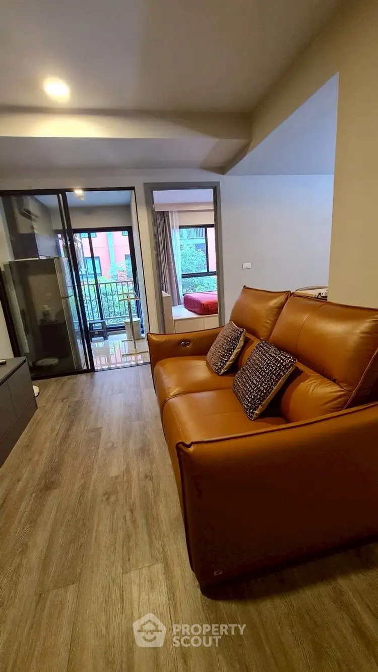 Modern living room with leather sofa and balcony view in stylish apartment.