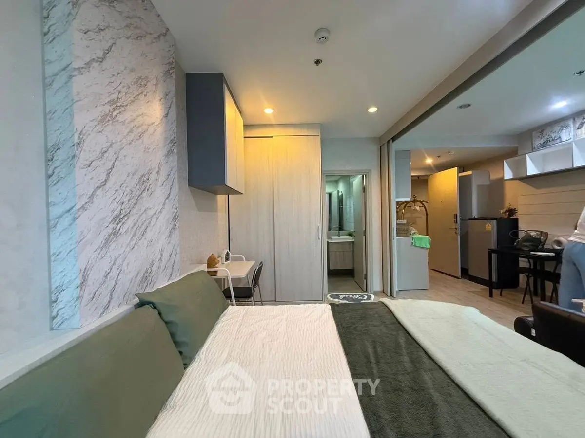 Modern bedroom with stylish decor and open layout leading to kitchen area.