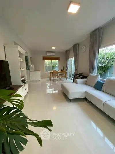 Spacious living room with modern decor and large windows offering garden views.