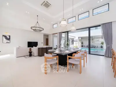 Luxurious open-plan living and dining area with pool view, high ceilings, and modern decor.