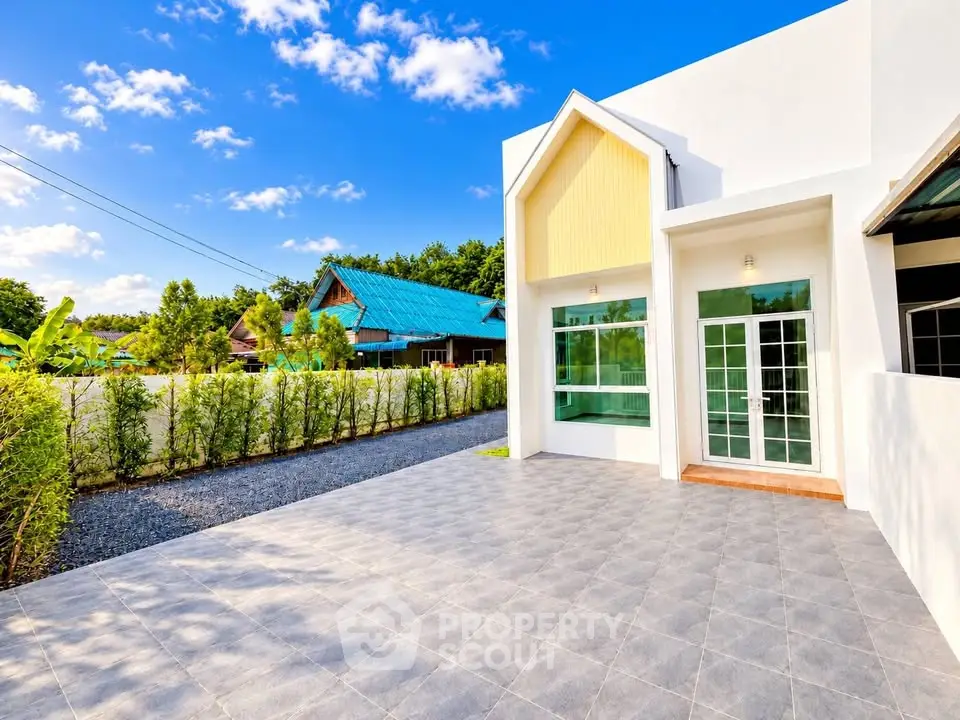 Modern house exterior with spacious tiled patio and lush greenery, perfect for outdoor living.