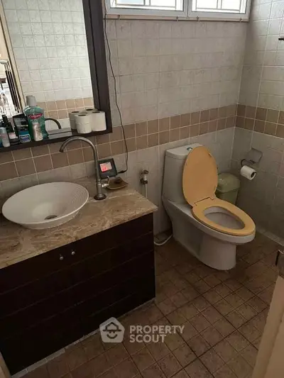 Cozy bathroom with modern sink and toilet, featuring neutral tiles and ample natural light.