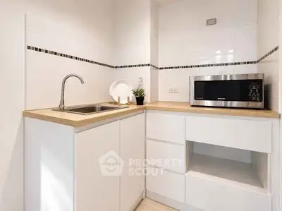 Modern compact kitchen with sleek white cabinets and built-in microwave