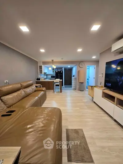 Spacious modern living room with open kitchen layout and stylish leather sofa.