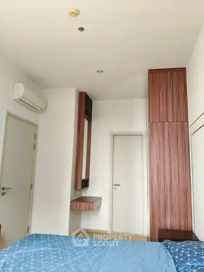 Modern bedroom with sleek wooden cabinetry and blue bedding