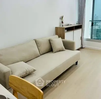 Modern living room with beige sofa and city view balcony, perfect for urban living.