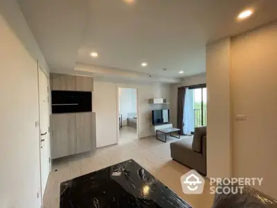 Modern living room with sleek furniture and natural light, featuring a cozy sofa and wall-mounted TV.