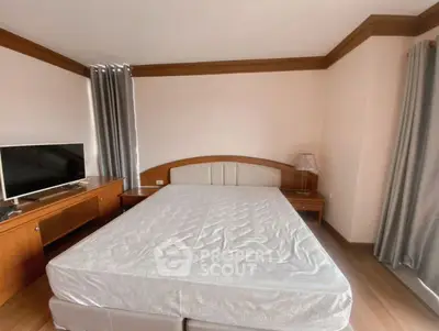 Spacious bedroom with wooden furniture and natural light, perfect for relaxation.