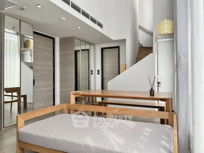 Modern duplex interior with wooden furniture and staircase, featuring natural light and sleek design.