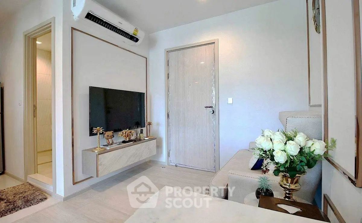 Modern living room with stylish decor and mounted TV, featuring elegant furniture and air conditioning.