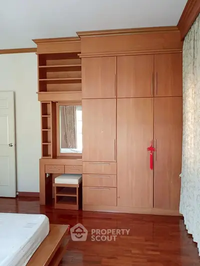 Spacious bedroom with built-in wooden wardrobe and vanity, perfect for organized living.