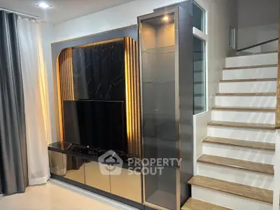 Modern living room with sleek TV unit and elegant staircase design