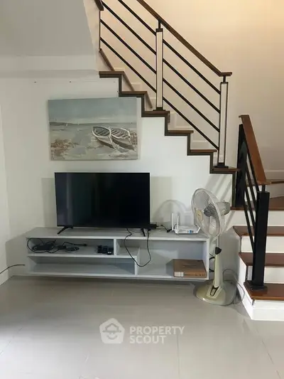 Modern living room with sleek staircase and entertainment setup