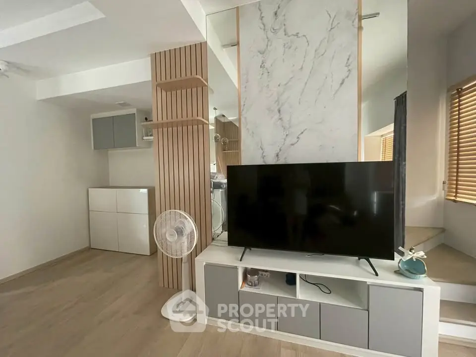 Modern living room with sleek TV stand and minimalist decor, featuring light wood flooring and stylish shelving.