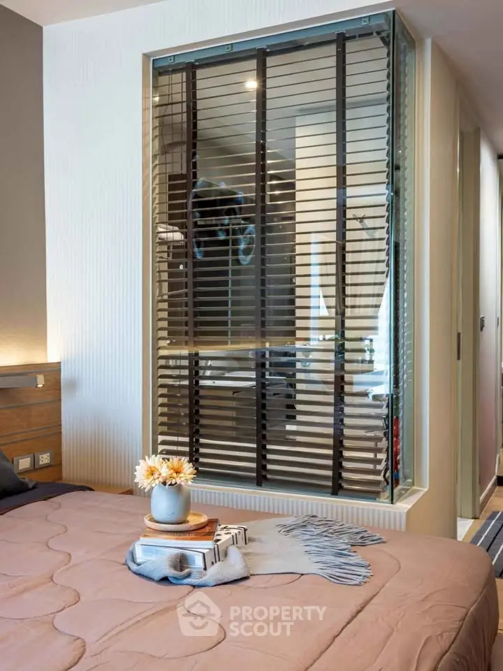 Modern bedroom with stylish decor and unique glass partition overlooking bathroom.
