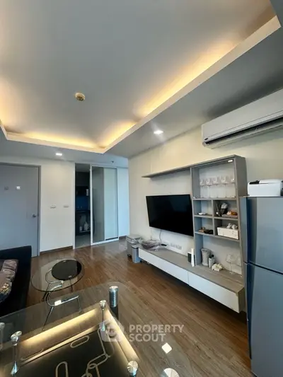 Modern living room with sleek design and open layout, featuring a wall-mounted TV and stylish furniture.