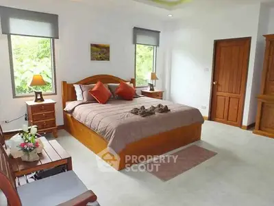 Spacious bedroom with wooden furniture and large windows offering natural light.