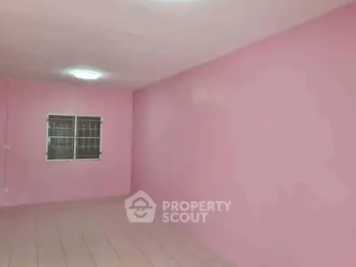 Spacious pink-walled room with tiled flooring and window, ideal for creative interior design.