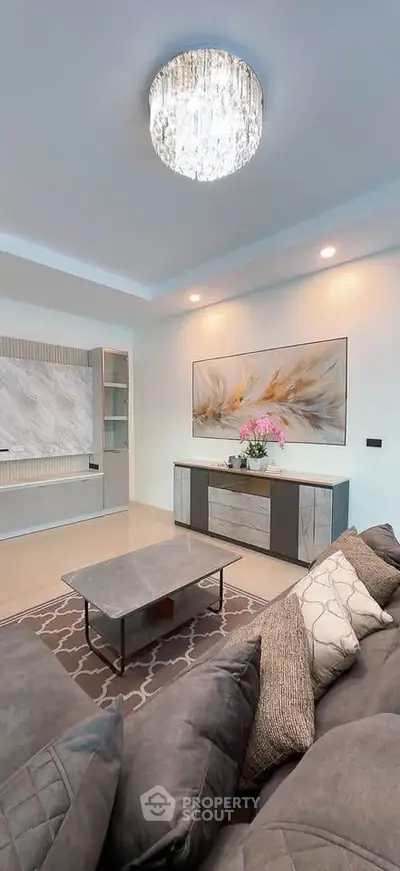 Elegant living room with modern decor, plush sofa, stylish coffee table, and chic lighting fixture.