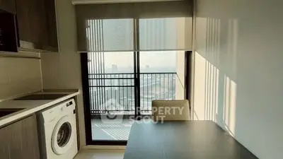 Modern kitchen with washing machine and balcony view in high-rise apartment.