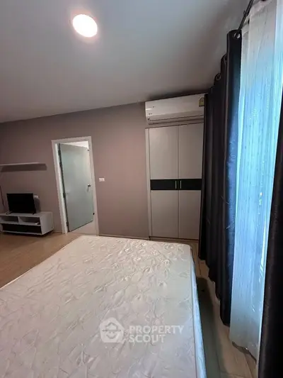 Cozy bedroom with natural light, featuring a comfortable bed, modern wardrobe, and air conditioning.