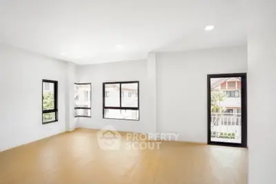 Spacious and bright living room with large windows and wooden flooring in modern home.