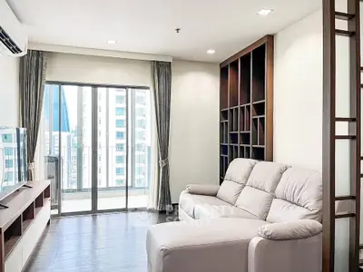 Modern living room with large windows and city view, featuring sleek furniture and stylish shelving.