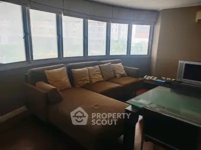 Spacious living room with large windows and modern furniture in urban apartment.