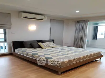 Spacious bedroom with modern decor and large windows for natural light.