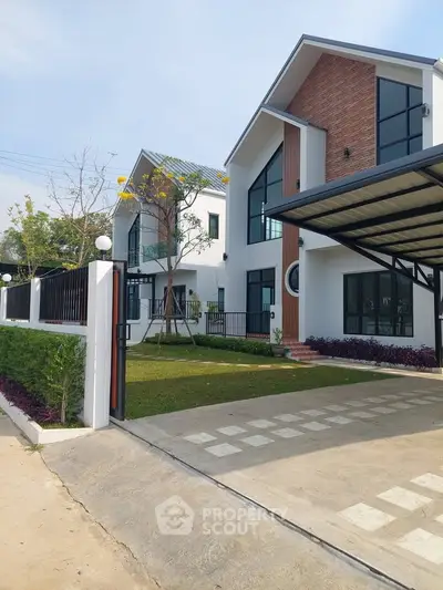 Modern two-story house with spacious driveway and landscaped garden, featuring contemporary architecture and large windows.