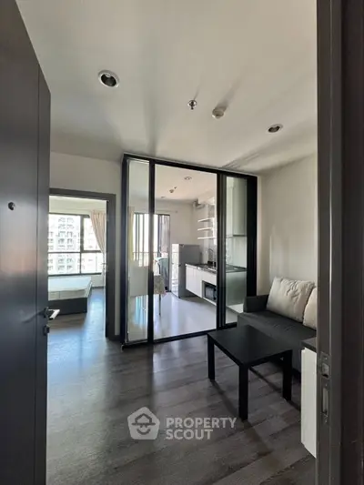 Modern apartment interior with open layout, featuring a cozy living area and a view of the bedroom and balcony.