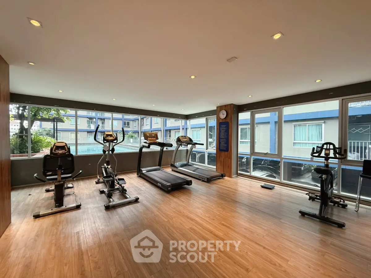 Spacious gym with modern equipment and large windows in a residential building.
