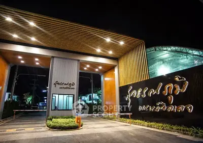 Elegant entrance of a modern residential complex with illuminated signage at night.