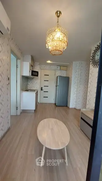 Modern living room with elegant chandelier and compact kitchen area.