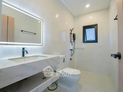 Modern bathroom with sleek fixtures and illuminated mirror in a contemporary home.
