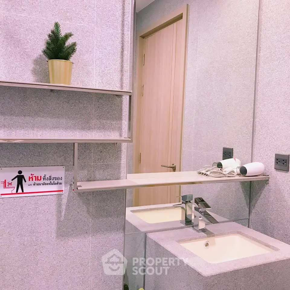 Modern bathroom with sleek sink and mirror, featuring minimalist decor and neutral tones.