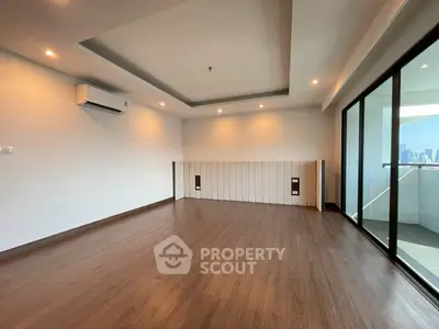 Spacious modern living room with wooden flooring and city view balcony.