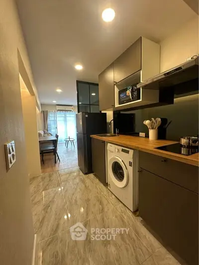 Modern kitchen with sleek appliances and open layout leading to a cozy living area.