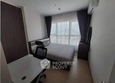 Modern bedroom with city view, featuring a sleek desk and comfortable chair, ideal for urban living.