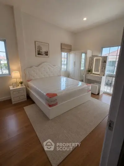 Spacious bedroom with elegant decor and natural light, featuring a plush bed and stylish furniture.