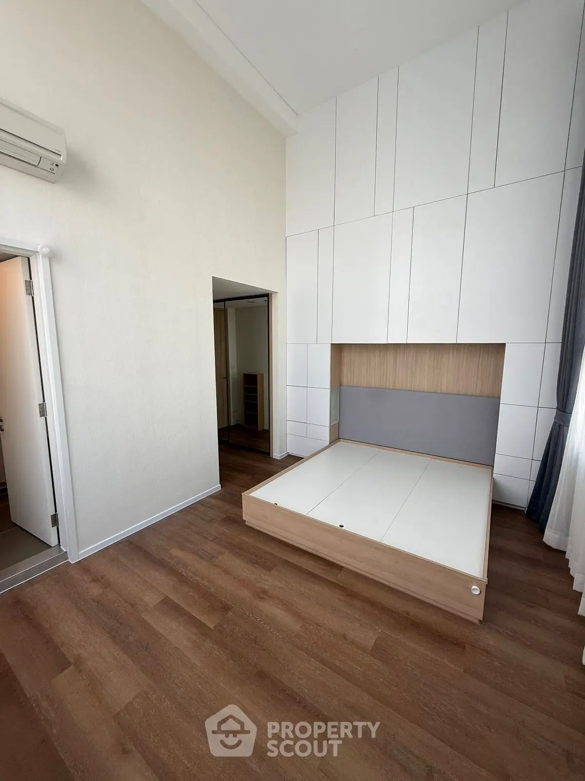 Spacious modern bedroom with built-in storage and wooden flooring