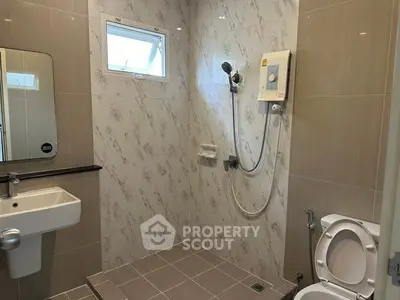 Modern bathroom with sleek tiles and shower area in a real estate property.