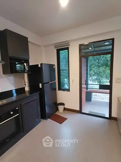 Modern kitchen with sleek black appliances and outdoor access