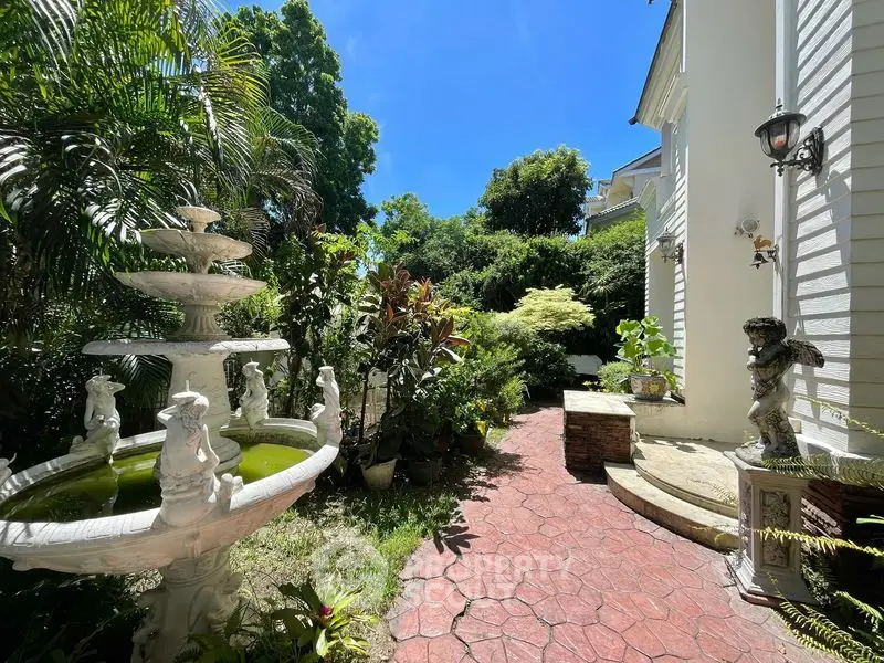 Charming garden with elegant fountain and lush greenery in a serene residential setting.